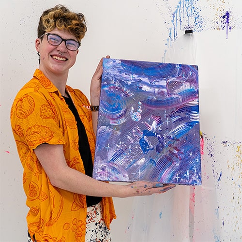 A person holding a painted canvas at Splash Lab